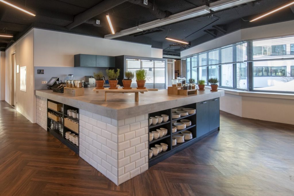 Keuken en uitgifte balie, uitgevoer met witte tegels , open vakken en een betonlook blad