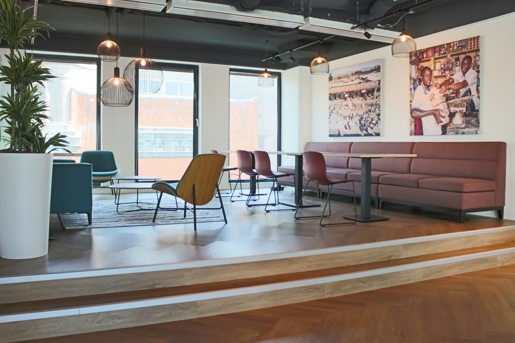 Loungehoek op podium met Leolux fauteuils en treinbanken met ronde tafeltjes en stoelen