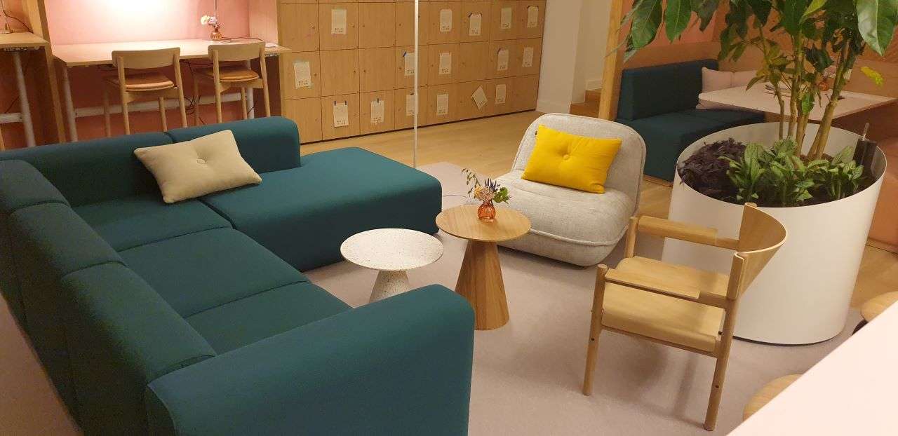 Donkergroene Hay bank in een hoek met een Puff fauteuil in zandkleur. gecombineerd met 2 ronde koffitafeltjes. Takt stoelen_ Puff fauteuil_bijzettafeltjes van Zuiver en fauteuil van Tact volledig in hout uitgeoverd. Interieurbouw lockers op de achtergrond.