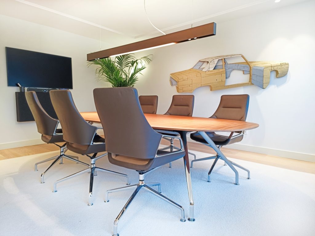 Luxe vergaderkamer met tafel en stoelen van Wilkhahn. Kunst als beleggingen in de vorm van een auto aan de wand.