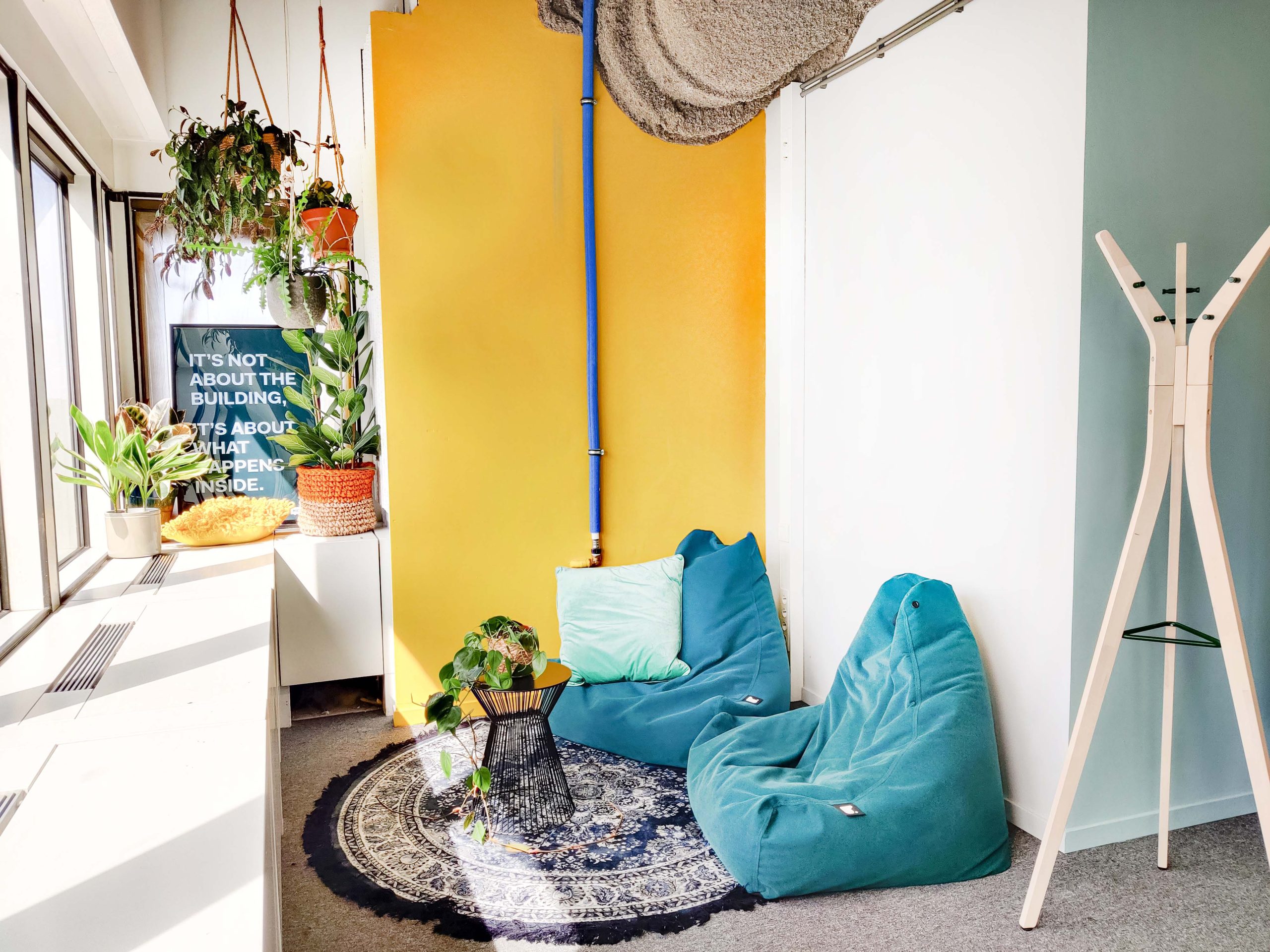 Varias Creative room met blauwe beenbags op een oosters kleed en tegen een gele muur